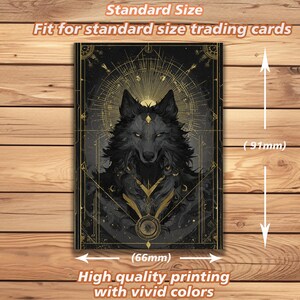 May include: A black and gold trading card with a detailed wolf illustration and celestial designs. The card measures 6.6cm wide and 9.1cm tall, suitable for standard trading cards. The text on the card reads "High quality printing with vivid colours."