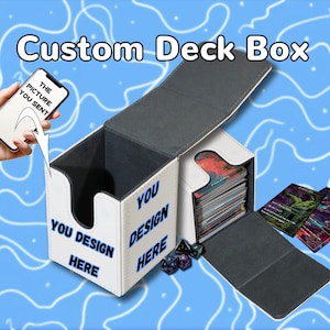 Könnte beinhalten: Eine weiße, individuell gestaltbare Kartenbox mit dunklem Innenraum und Klappdeckel. Die Außenseite trägt den blauen Schriftzug "YOU DESIGN HERE". Ein Smartphone zeigt "THE PICTURE YOU SENT" mit einem Pfeil zur Box. Spielkarten und Würfel liegen bei.