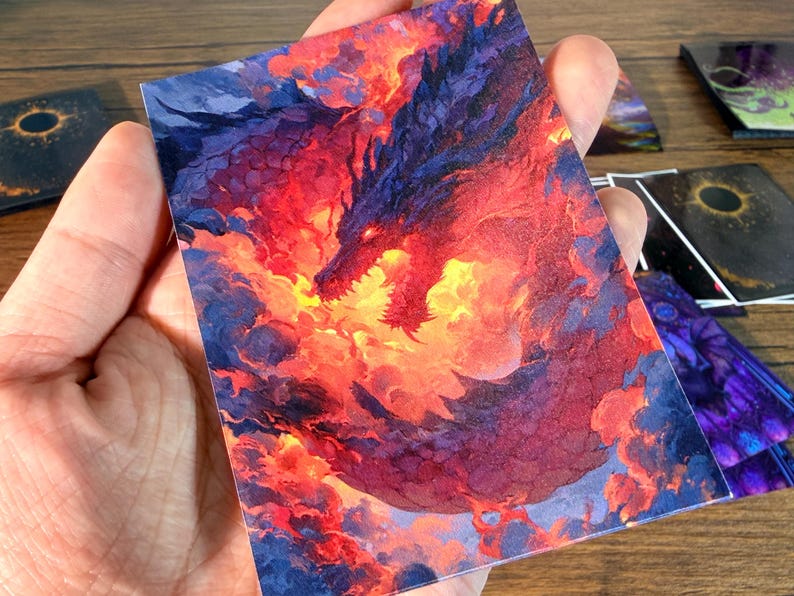 Pu&ograve; includere: Una carta artistica fantasy con un drago rosso e viola avvolto dalle fiamme. La testa del drago &egrave; visibile, con la bocca aperta, su uno sfondo infuocato. Altre carte con disegni simili sono visibili sullo sfondo.