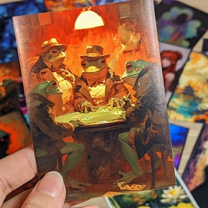 Puede incluir: Una impresión en madera que representa una partida de póquer con ranas antropomórficas con sombreros y trajes. Las ranas están reunidas alrededor de una mesa verde, jugando a las cartas bajo una iluminación cálida. Otras impresiones artísticas son visibles en el fondo.