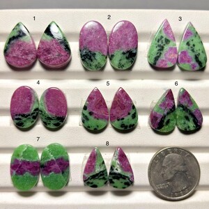May include: Eight pairs of polished ruby zoisite cabochons arranged in a grid, numbered one through eight. Each stone features a unique pattern of vibrant pink, bright green, and black inclusions. A United States quarter is included for scale.