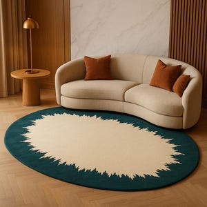 Puede incluir: Una alfombra ovalada con un centro color crema y un borde verde oscuro. El borde tiene un borde irregular y orgánico. Un sofá beige curvado con cojines marrones se encuentra en el fondo, creando una escena de sala de estar acogedora.