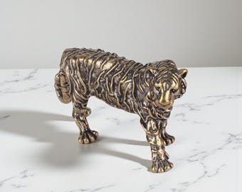 May include: A bronze-colored tiger figurine with detailed fur texture. The sculpture is posed in a standing position, showcasing its front legs and head. The figurine is a decorative item, suitable for home decor.