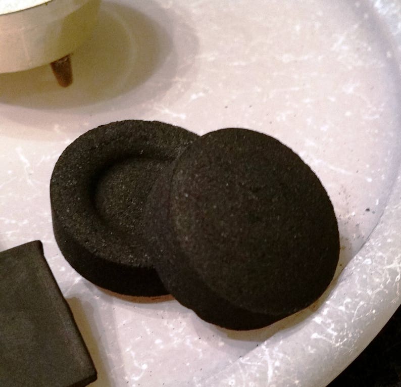 May include: Two round black charcoal briquettes for a hookah or shisha pipe.