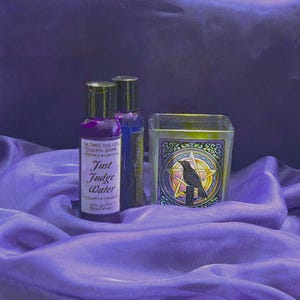 May include: A still life featuring two small bottles of purple liquid labeled "Just Judge Water" and a blue bottle. A square glass candle holder with a raven and pentagram design is also present. The items are arranged on a purple fabric.