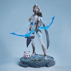 Puede incluir: Figura detallada de un personaje con un atuendo blanco y dorado, sosteniendo un arco y flecha azules. La figura se encuentra sobre una base de piedra con una pequeña criatura peluda con un corazón en el pecho. El personaje tiene una capucha y capa.