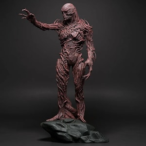 May include: A detailed, reddish-brown statue of a humanoid creature with a textured, vine-like appearance. The figure stands on a dark, rocky base, with one arm outstretched and claw-like hands. The overall design suggests a fantasy or horror theme.