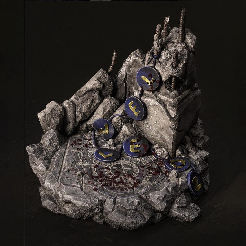 May include: A detailed miniature diorama featuring a stone structure with a circular base and jagged edges. Dark blue circular charms with gold lettering are connected by a blue string. The base has a pattern and red splatters.