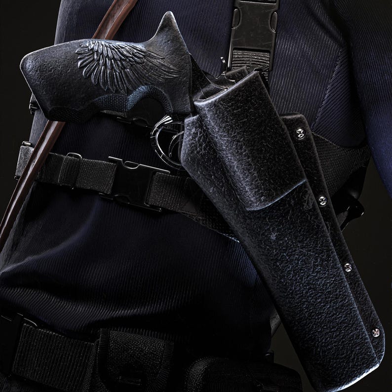 May include: Close-up of a black pistol with an ornate wing design on the handle, holstered on a person's side. The holster is textured and secured with a belt and straps. The person is wearing a dark blue uniform.