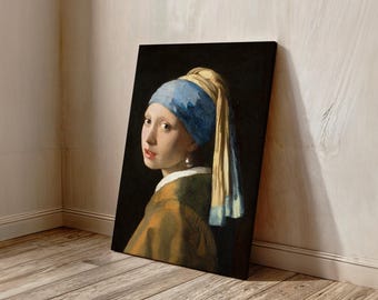 Puede incluir: Una impresión en lienzo de "La joven de la perla" de Johannes Vermeer. La obra presenta a una joven con un pañuelo azul y amarillo, un pendiente de perla y una chaqueta color mostaza sobre un fondo oscuro. La pintura está apoyada contra una pared.