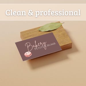 May include: A business card for "Bakery Petite Crumb" with a watercolor macaron illustration. The card is on a wooden block, with a leaf on top. The text "Clean & professional" is at the top.