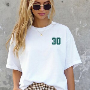Op de afbeelding: Wit T-shirt met het nummer 30 in een groene, omrande letter. Dit casual T-shirt is geschikt voor dagelijks gebruik. Het nummer staat op de borst.