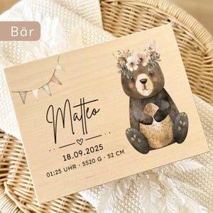 May include: A wooden plaque featuring a watercolor illustration of a bear wearing a floral crown. The plaque includes the name "Matteo", birthdate, time, weight (5520 grams), and length (52 cm). A small banner with pastel flags is also present.