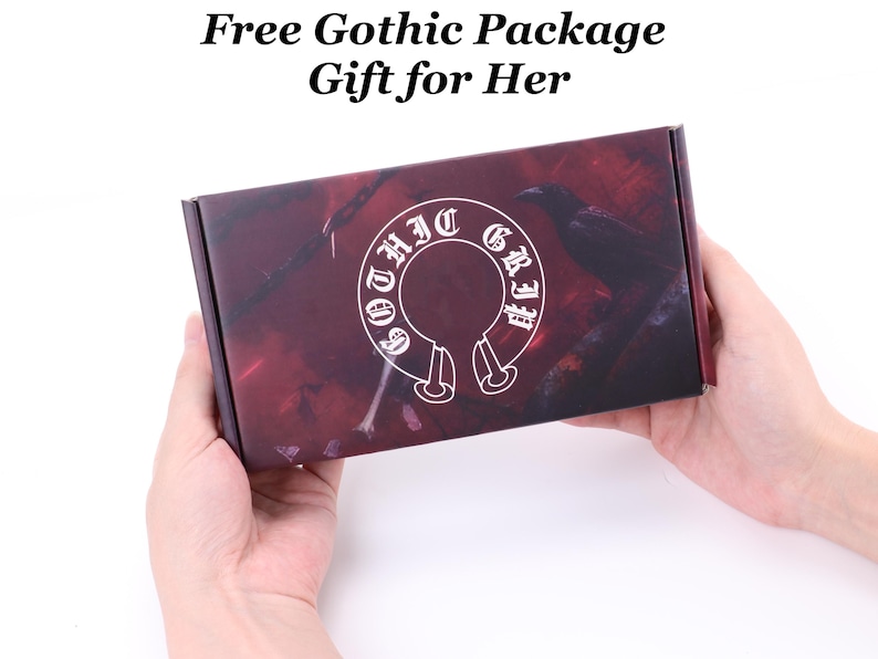 May include: A rectangular box with a dark red and black design, held by two hands. The box features a white emblem with the words "Gothic Girl" and a raven silhouette. Above the box, the text reads "Free Gothic Package Gift for Her."