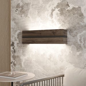 May include: A rectangular wooden wall sconce with a dark wood grain finish and a black accent stripe. The sconce emits a warm, diffused light. The fixture is mounted on a wall with a cloudy, textured wallpaper.