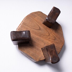 Puede incluir: Escultura de madera hecha a mano con una base irregular de color marr&oacute;n claro y tres bloques rectangulares de color marr&oacute;n oscuro. La escultura es de madera y tiene un acabado natural. La base mide unos 20 cm de di&aacute;metro.