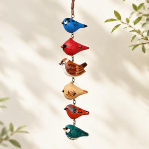 May include: A decorative mobile with six wooden birds in various colours, suspended from a brown leather cord. The birds are linked by small metal rings. The birds are painted in blue, red, brown, tan, orange, and teal.