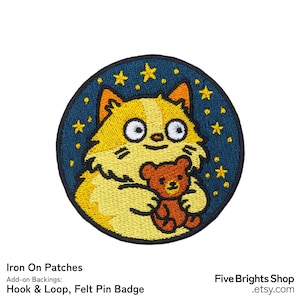 May include: Round iron-on patch featuring a cartoon cat holding a teddy bear. The cat is yellow and white with large eyes, set against a dark blue background with yellow stars. The patch has the text "Iron On Patches".