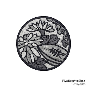 Könnte beinhalten: Runder, gestickter Aufnäher mit einem floralen Design in Grau- und Schwarztönen. Der Aufnäher zeigt eine Chrysantheme, eine Lotusblume und stilisierte Elemente. Er hat einen schwarzen Rand und ist für Kleidung oder Accessoires geeignet.