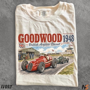 May include: An ivory t-shirt featuring a graphic print of vintage race cars on a track. The text reads GOODWOOD 1948 British Airfield Circuit. The illustration depicts a red car numbered 25 and a green car numbered 16 at a historic racing event.