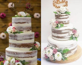 Puede incluir: Un pastel de boda de tres pisos con un diseño rústico de veta de madera. El pastel está decorado con flores frescas y vegetación, y un letrero que dice "Mr. & Mrs. Bellman".