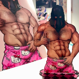 May include: An acrylic standee featuring a muscular figure wearing a black hood and pink shorts with a white cat print. The figure is posed with a thumb up, standing on a pink and black checkered base, with a matching print displayed behind it.