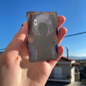 Puede incluir: Una tarjeta rectangular con una ilustración en escala de grises de una persona con los brazos levantados, enmarcada por una forma más oscura. Un pequeño símbolo de corazón flota sobre la cabeza de la persona. El fondo es un degradado azul y gris.