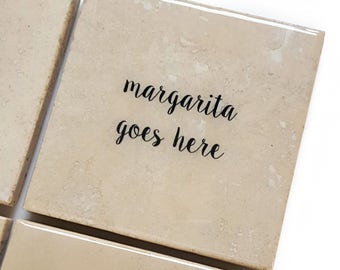Può includere: Sottobicchieri quadrati beige con la scritta "margarita goes here" in corsivo nero. I sottobicchieri hanno una finitura lucida e un aspetto di pietra naturale. Ideali per proteggere le superfici dalla condensa.