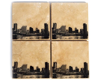 Peut inclure: Ensemble de quatre sous-verres en céramique beige avec une silhouette noire d'une ville imprimée sur chaque sous-verre.