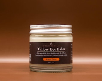 May include: A glass jar of Holistic Heritage Tallow Bee Balm with a silver lid. The label reads "Tallow Bee Balm" and "Citrus Grove". The jar contains a creamy, off-white balm. The text on the label also mentions it is made with Irish grass-fed organic beef suet.