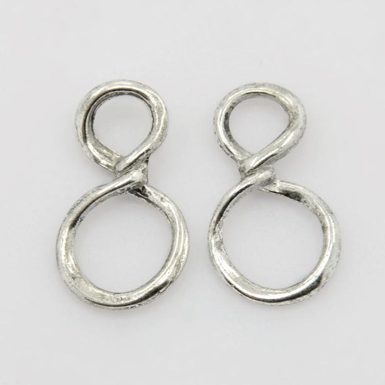 May include: A pair of silver infinity symbol earrings. The earrings are made of twisted metal and have a textured finish.