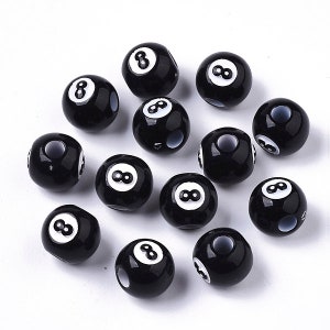 May include: A collection of 12 black and white 8-ball themed beads. Each bead features a white number 8 on a black background.