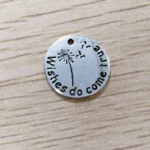 May include: Silver charm with a dandelion design and the text "Wishes do come true".