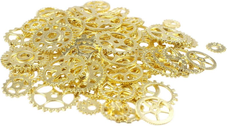 May include: A collection of small, gold-colored metal gears of various sizes, scattered against a white background. The gears have intricate designs with multiple spokes and circular holes, suggesting a steampunk or industrial theme.
