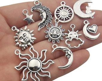 May include: A collection of silver-toned metal charms featuring various celestial designs, including suns, moons, and stars. The charms have intricate details and are perfect for jewelry making or crafting.