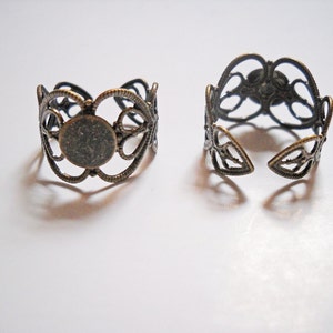 May include: Two antique gold-toned metal rings with an open design. The rings are made of delicate filigree and have a circular opening in the center.
