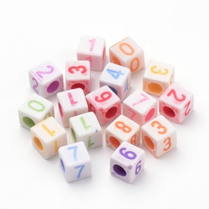 May include: A collection of 16 white plastic cubes with colorful numbers painted on each side. The numbers range from 0 to 9.