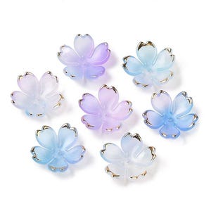 May include: Seven iridescent flower-shaped beads with gold trim. The beads are in shades of blue and purple.