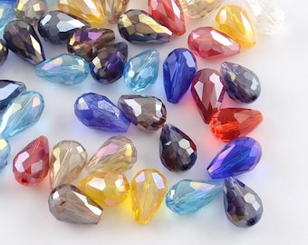 May include: A collection of faceted teardrop-shaped beads in various colors, including blue, red, yellow, and iridescent hues. The beads are scattered, showcasing their glossy surfaces and intricate cuts. These beads are suitable for jewelry making and crafting projects.