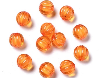 Puede incluir: Una colección de 12 cuentas de plástico de color naranja con forma de calabaza y textura acanalada. Las cuentas tienen un diámetro aproximado de 2,5 cm.