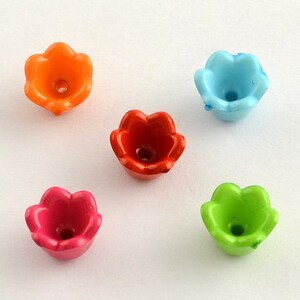 May include: Five plastic flower-shaped beads in different colors: orange, red, light blue, green, and pink. The beads have a small hole in the center for stringing.