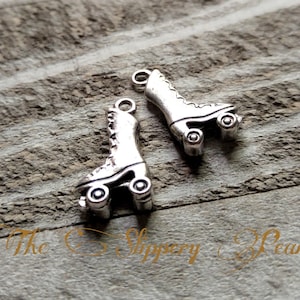 May include: Two silver roller skate charms with a detailed design. The charms have a loop at the top for attaching to a necklace or bracelet.