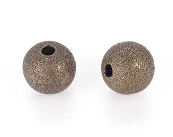 May include: Two textured, bronze-colored spherical beads with a hole drilled through each. The beads have a rough, pitted surface. These beads are suitable for jewelry making and crafting projects.