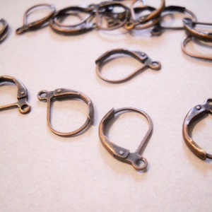 May include: A close-up of a pile of antique bronze earring hooks. The hooks are made of metal and have a spring-loaded clasp.