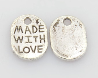 May include: Two silver oval-shaped metal charms with a hole at the top for hanging. One charm has the words "MADE WITH LOVE" engraved on it.