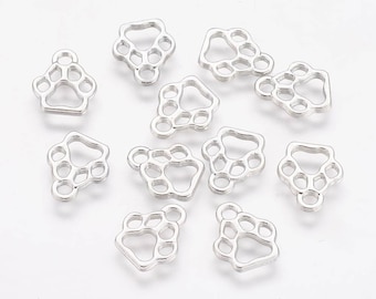 May include: A selection of silver paw print charms. Each charm has a paw print design with five toe pads and a loop for attachment to jewellery or crafts. The charms are scattered on a white surface.