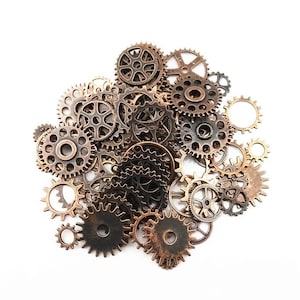 May include: A collection of antique-looking metal gears in various sizes and shapes, arranged in a cluster on a white background.