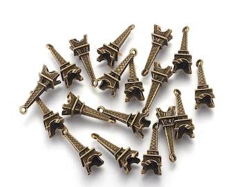 May include: A collection of 16 antique gold Eiffel Tower charms. The charms are made of metal and have a detailed design. They are perfect for adding a touch of Parisian style to jewelry or crafts.