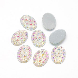 May include: Eight oval-shaped iridescent rhinestones with a flat back. The rhinestones have a clear base with a rainbow of colors embedded in the surface.