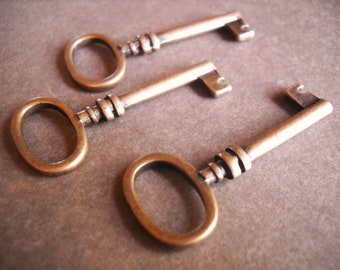 May include: Three antique-style keys with ornate metalwork and a brass finish. The keys have different shapes and sizes, with one key having a larger, rounder head.